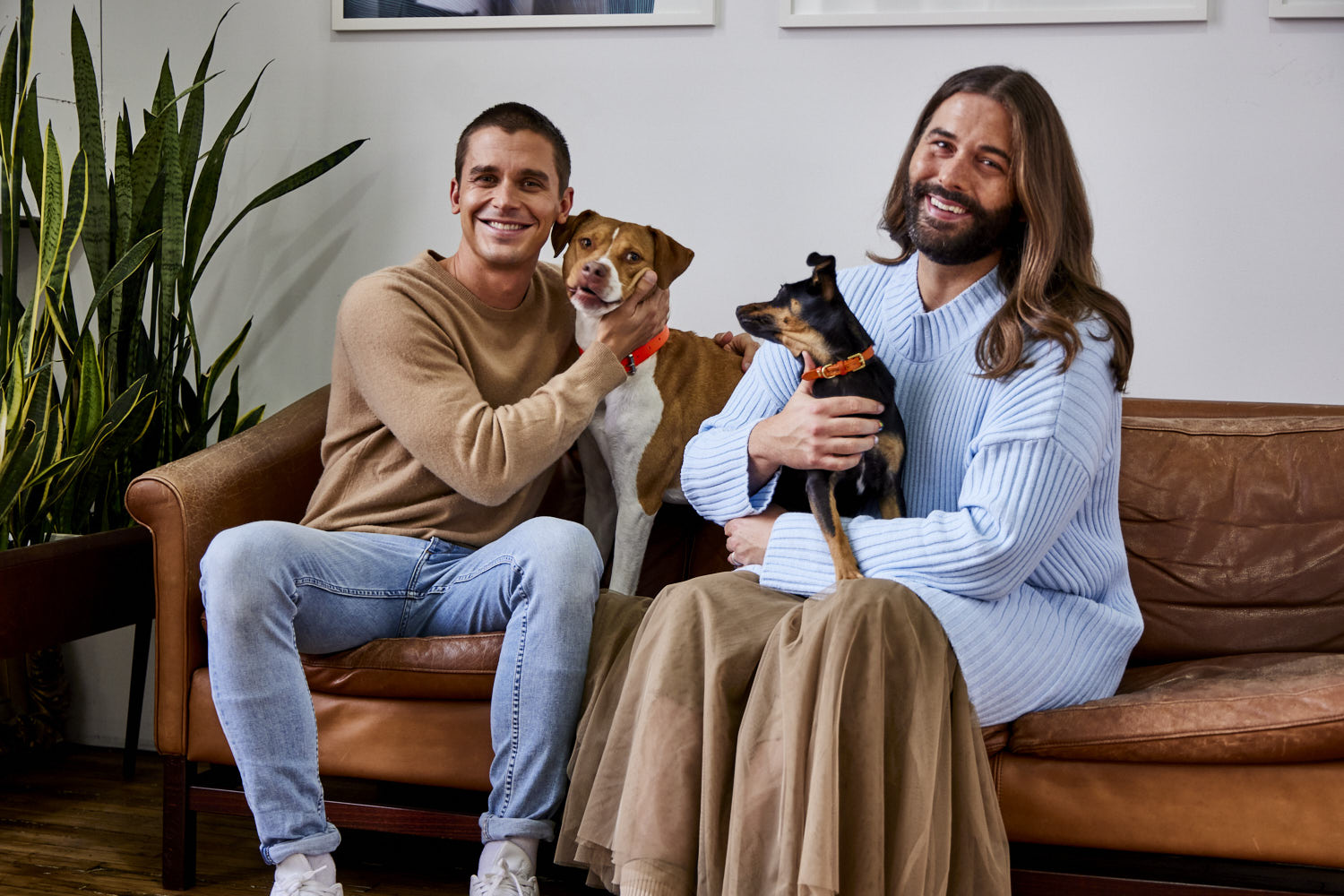 Antoni Porowski and Jonathan Van Ness (“JVN”) sitting on a couch with their dogs